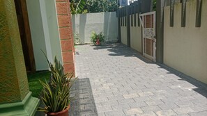 Un patio empedrado con una planta en maceta y una pared con una puerta.