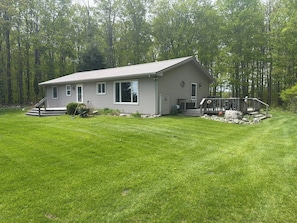 A single-story house with a front porch, a small front yard, and a wooded area in the background. - 80-Acre Northern Michigan Lodge~Trails & Fire Pit (Wolverine)