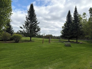 A grassy field with a wooden gazebo and tall trees. - 80-Acre Northern Michigan Lodge~Trails & Fire Pit (Wolverine)
