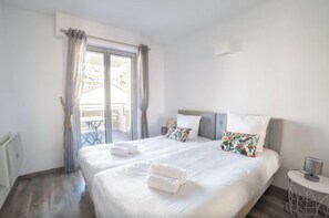 Een hotelkamer met twee bedden, een balkon en een kleine tafel met een lamp.