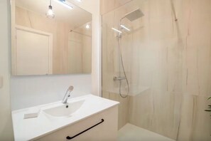 Ein modernes Badezimmer mit Waschbecken, Spiegel und Dusche in Weiß.