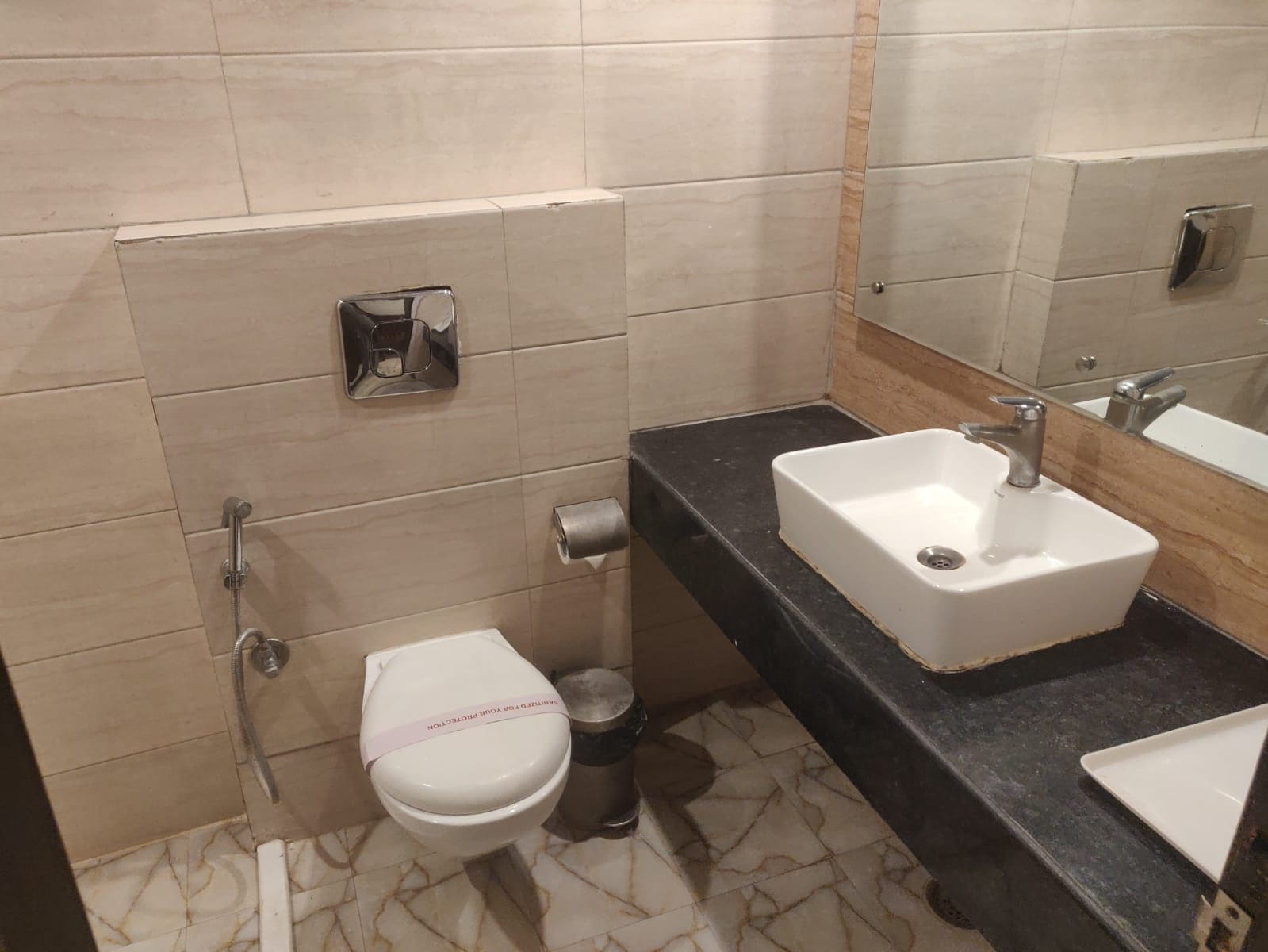 A bathroom with a toilet, a sink, and a mirror.