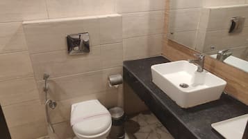 A bathroom with a toilet, a sink, and a mirror.