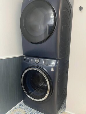 A stacked washer and dryer unit in a corner with a tiled floor. - Waterfront Lake Charlevoix|Private Dock, Fire Pit (Boyne City)
