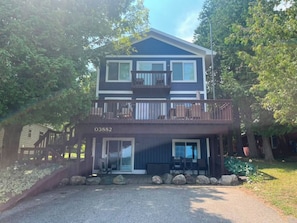 A two-story building with a balcony, a number '03882' on the front, and a gravel driveway. - Waterfront Lake Charlevoix|Private Dock, Fire Pit (Boyne City)
