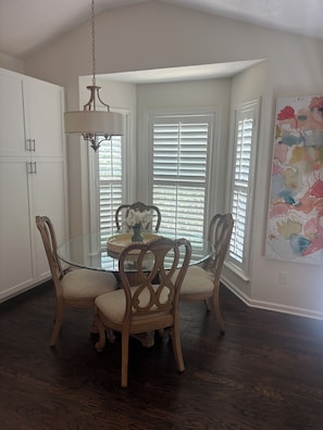 A dining area with a glass table, wooden chairs, a chandelier, and a window with blinds. - Life on the Lake, Come on down to South GA, only three miles to the Fl. line (Lake Park)