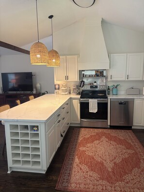 A modern kitchen with white cabinetry, a large island, a built-in oven, a dishwasher, and a TV. - Life on the Lake, Come on down to South GA, only three miles to the Fl. line (Lake Park)