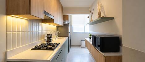 Una cocina moderna con estufa a gas, cafetera y microondas.