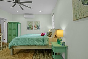 A bedroom with a bed, a nightstand, a lamp, a green cabinet, and two wall art pieces. - Cozy 1-bedroom studio apartment with a perfect blend of style and tranquility (Nassau)
