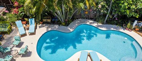 A swimming pool with lounge chairs and tropical plants.