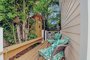 A wooden deck with two chairs and a small wooden structure, surrounded by lush greenery. - Cozy 1-bedroom studio apartment with a perfect blend of style and tranquility (Nassau)