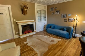 A living room with a fireplace, a blue sofa, a fur rug, and wall-mounted pictures.