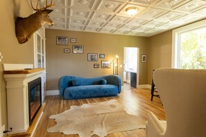 A room with a fireplace, a blue sofa, a fur rug, and a deer head mounted on the wall. - Hot Springs Spa room (Salida)