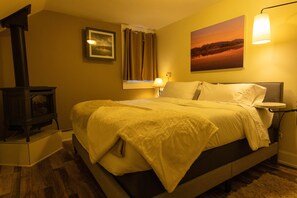 Quarto com cama, luminária na parede, pintura e lareira.