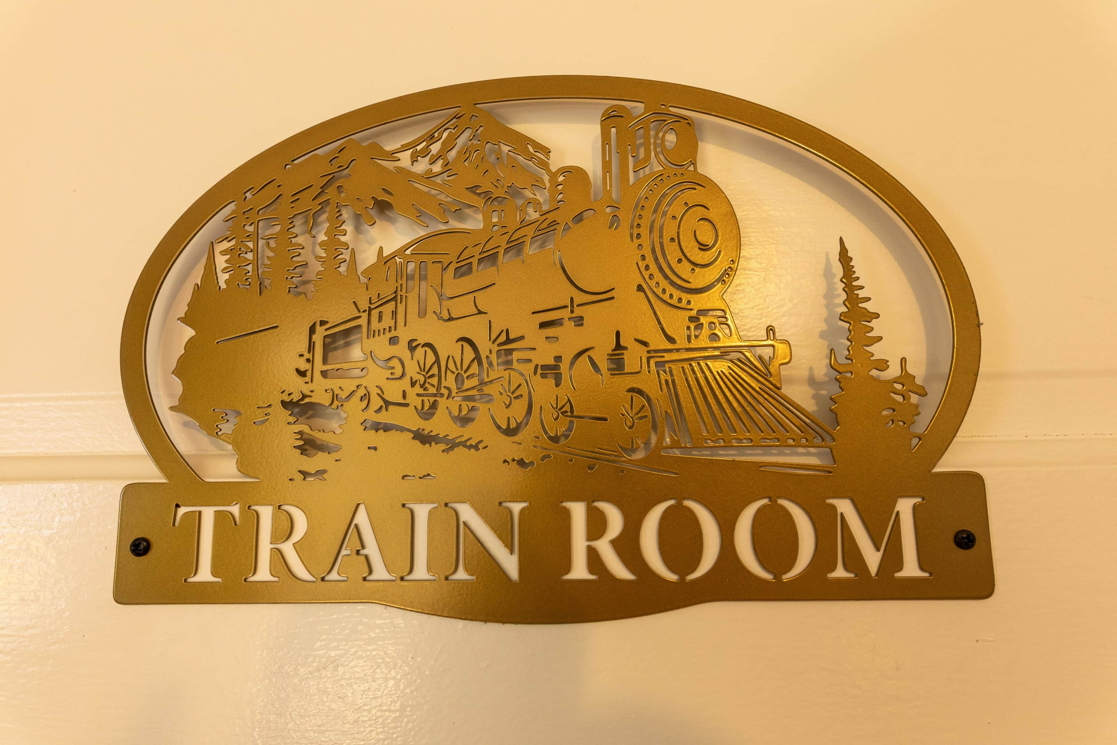 A wall-mounted sign with a cut-out design depicting a train and the words 'TRAIN ROOM'.