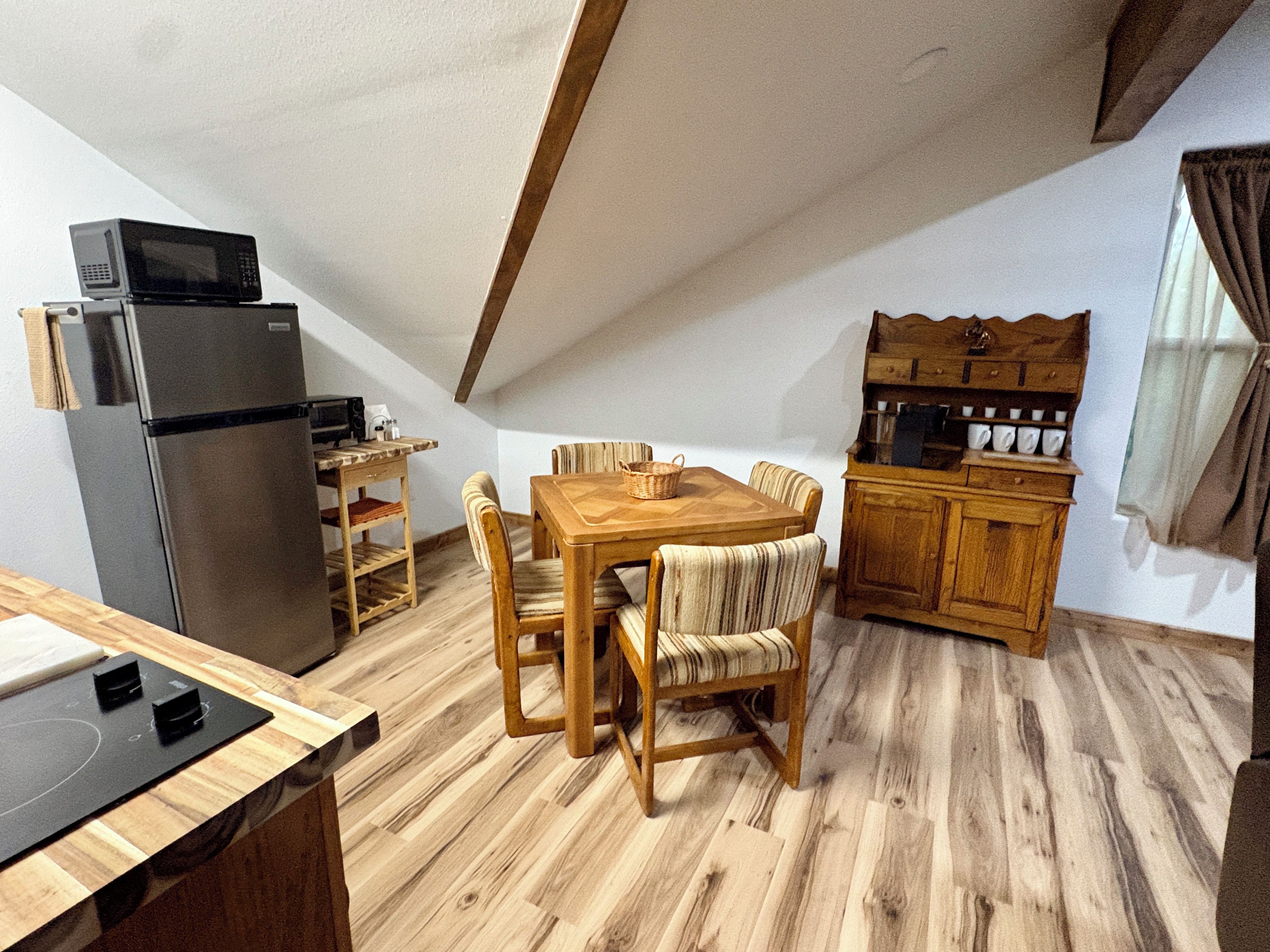 Una cocina compacta con refrigerador, microondas y armarios de madera.