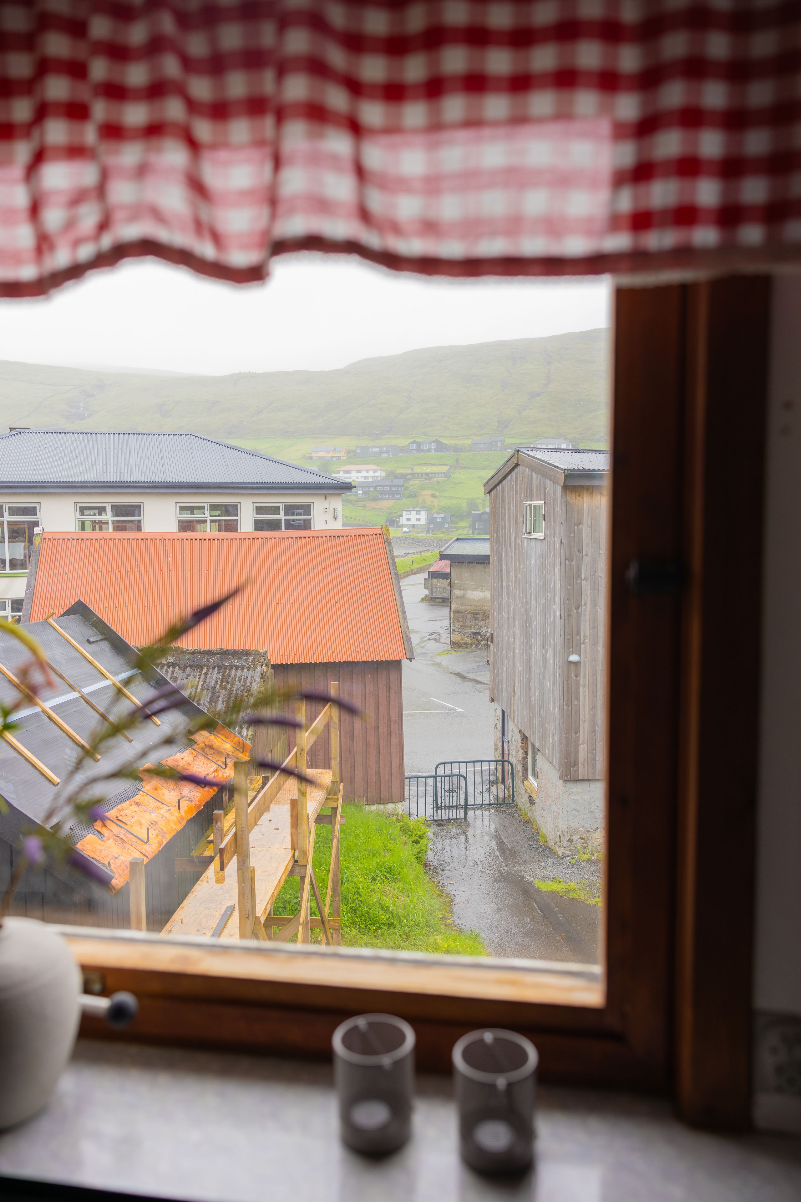 A view from a window overlooking a rural landscape with buildings and a road.
