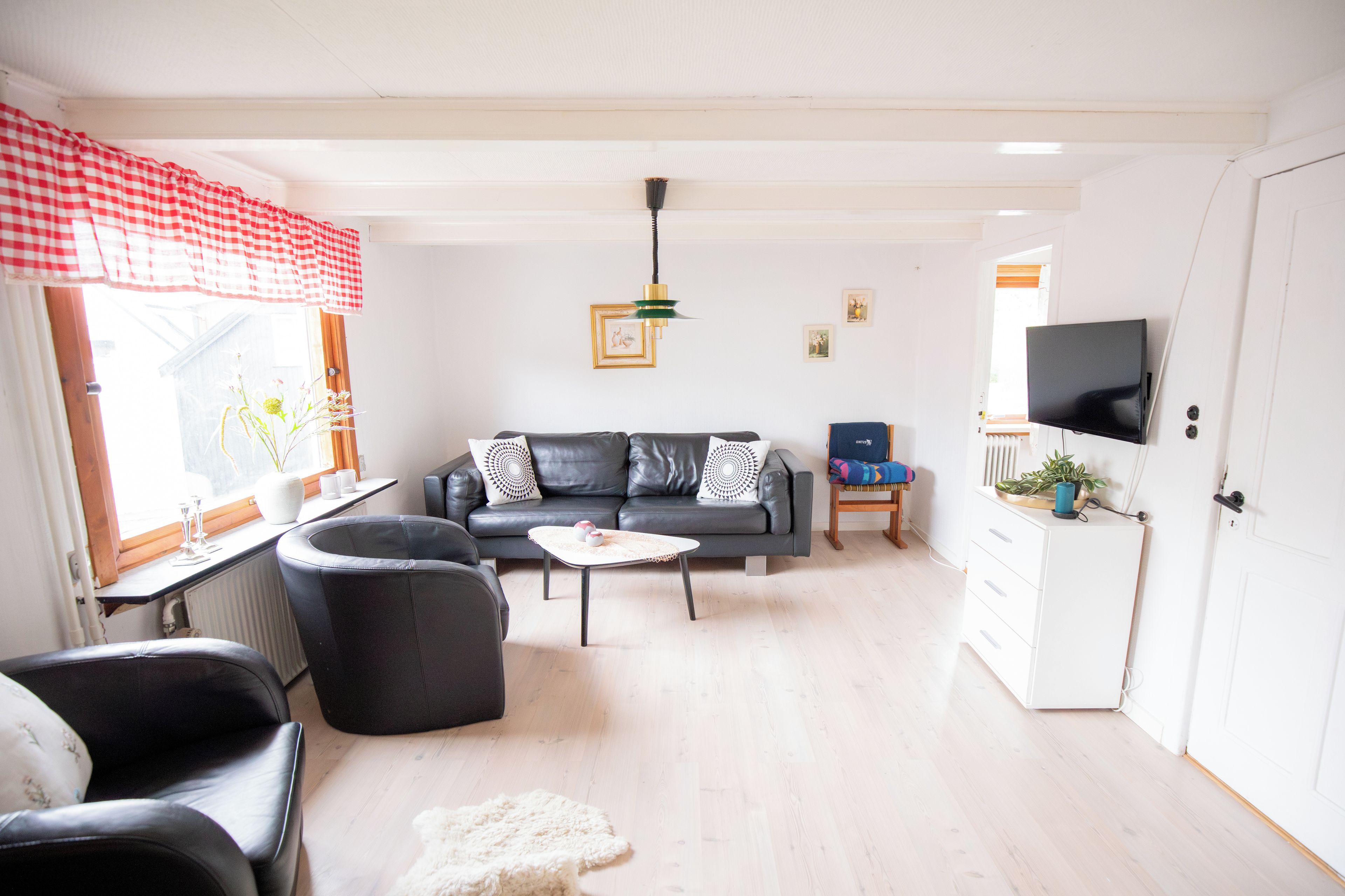 A living room with a sofa, chairs, a coffee table, a television, and a radiator.