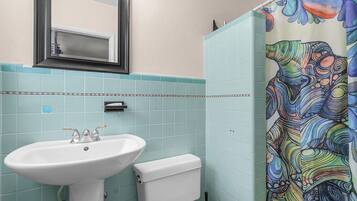 A bathroom with a white sink, a toilet, and a shower curtain with a colorful abstract pattern.