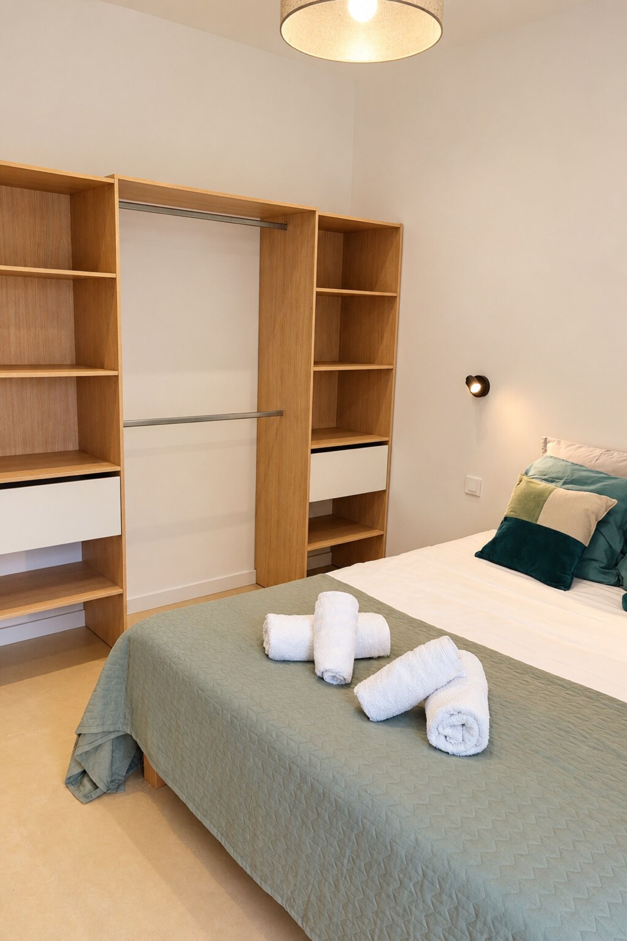Un dormitorio con cama, armario y lámpara de noche.