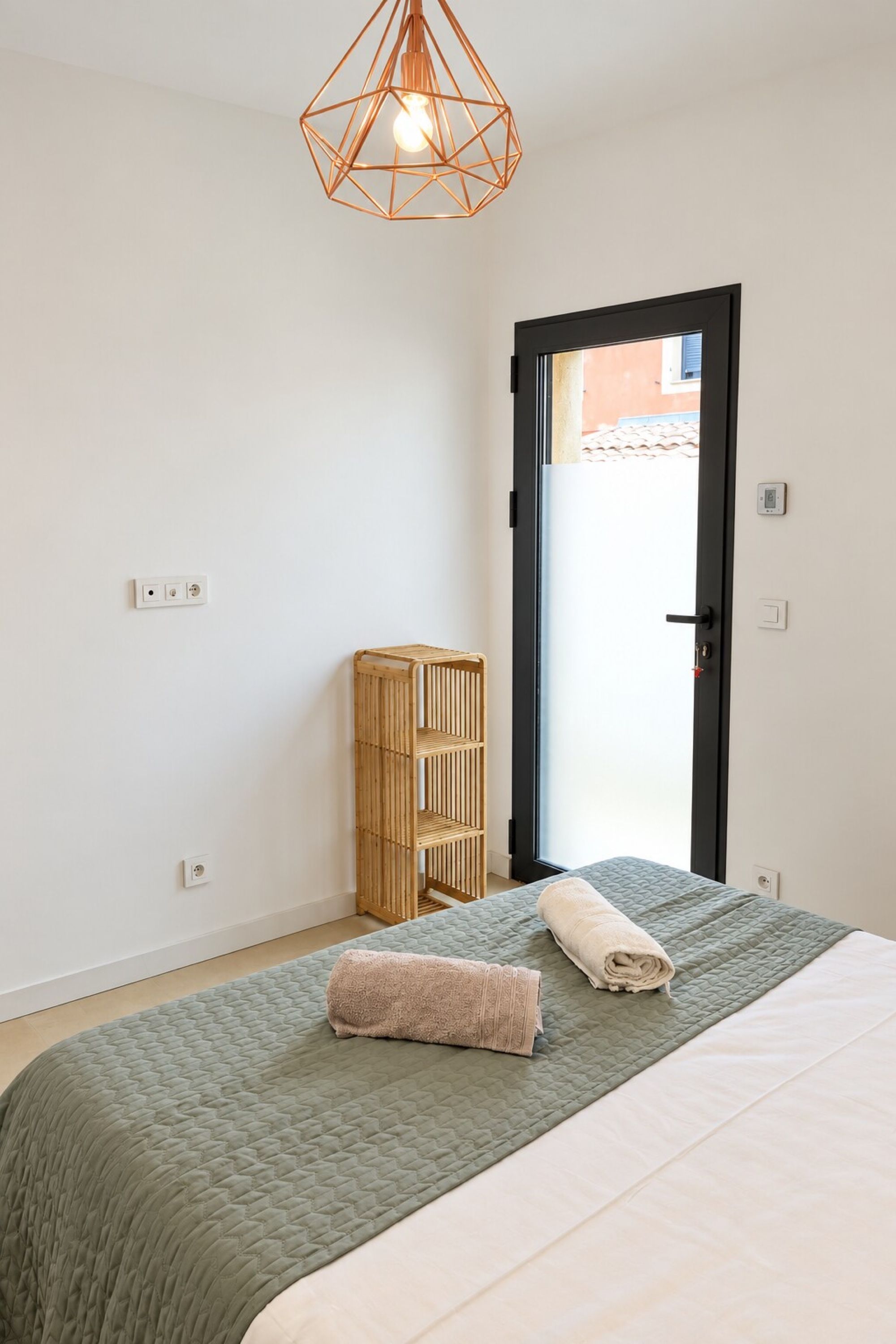 Une chambre à coucher avec un lit, une armoire en bois et un luminaire au design géométrique.