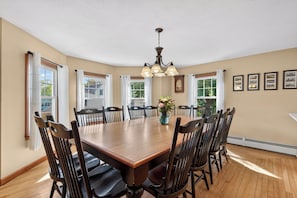 A dining room with a large wooden table, multiple chairs, a chandelier, and framed pictures on the walls. - Beautiful 5-bedroom house with AC 5-min walk to Old Orchard Beach (Old Orchard Beach)