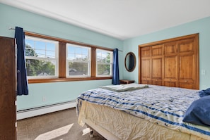 Ein Schlafzimmer mit Bett, Fenster, Kleiderschrank und Spiegel.