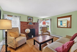 A living room with a fireplace, two armchairs, a coffee table, and a lamp. - Beautiful 5-bedroom house with AC 5-min walk to Old Orchard Beach (Old Orchard Beach)