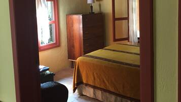 A bedroom with a bed, a dresser, a desk, and a window with curtains.
