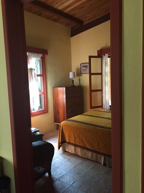 A bedroom with a bed, a dresser, a desk, and a window with curtains.