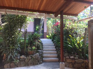 Un escalier extérieur abrité, entouré d’une végétation luxuriante et de plantes.