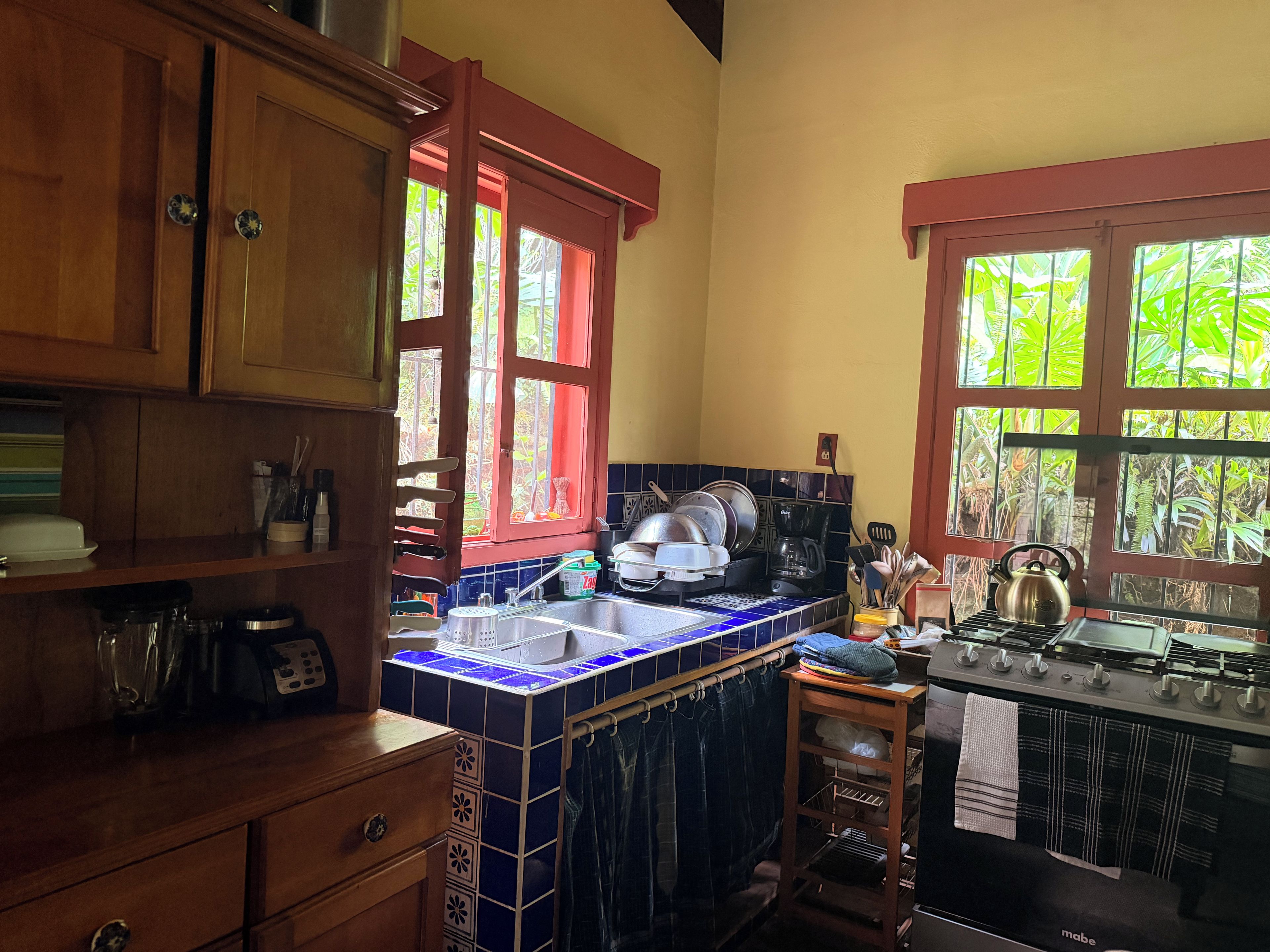 A kitchen with wooden cabinets, a tiled backsplash, a sink, and a stove.