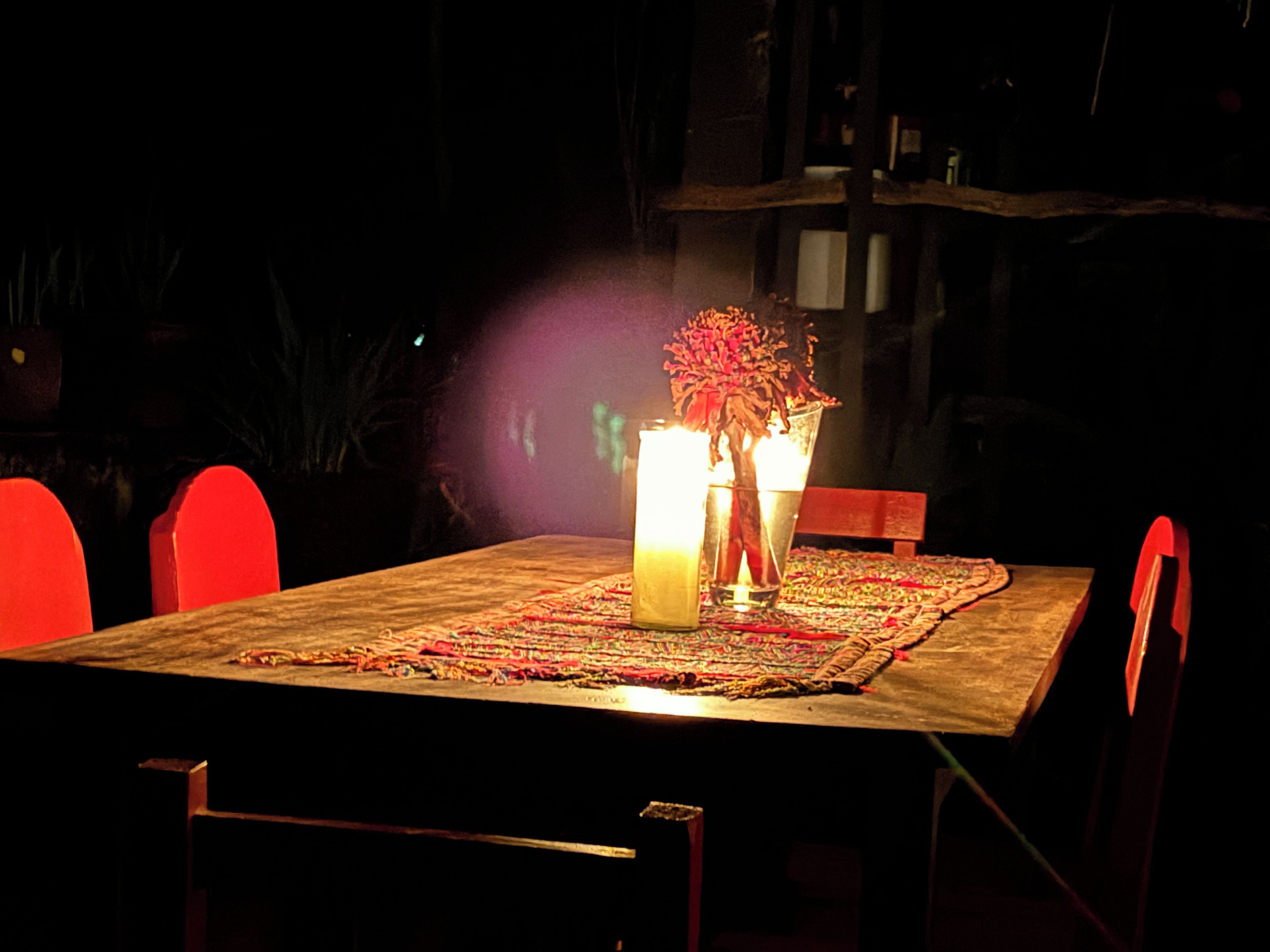 A dining table with chairs, candles, and a centerpiece.