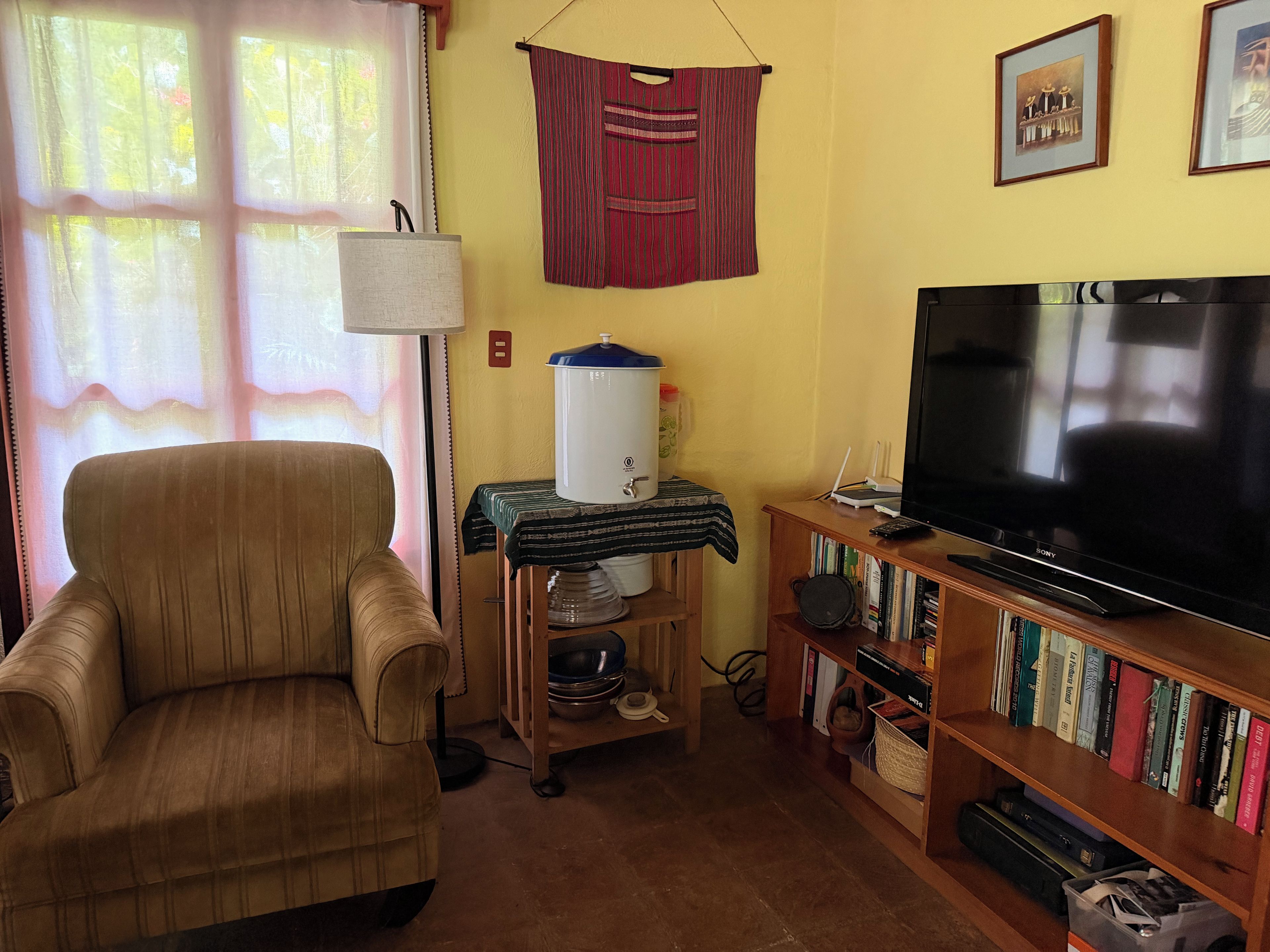 A living room with a sofa, a television, a bookshelf, and a water heater.