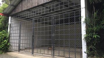 A metal gate with a grid pattern, attached to a concrete wall with a white base.
