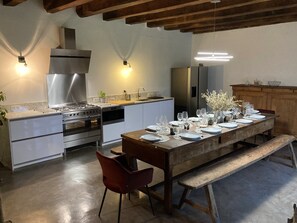 A modern kitchen with stainless steel appliances, a wooden dining table set for six, and a bench. - Renovated villa with 2 swimming pools and a hot tub (Latronquière)