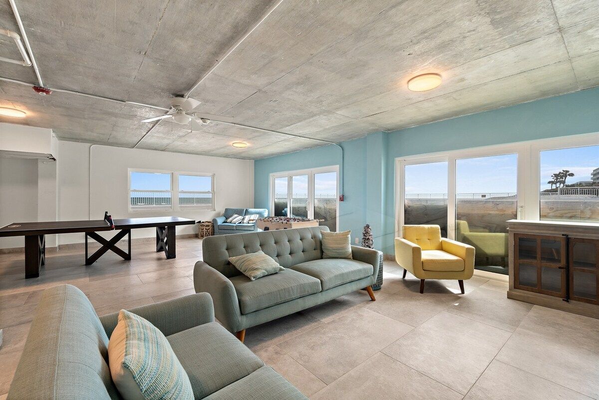 A spacious living area with a sofa, armchairs, a coffee table, and a pool table.