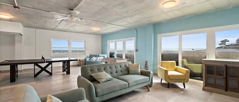 A spacious living area with a sofa, armchairs, a coffee table, and a pool table.