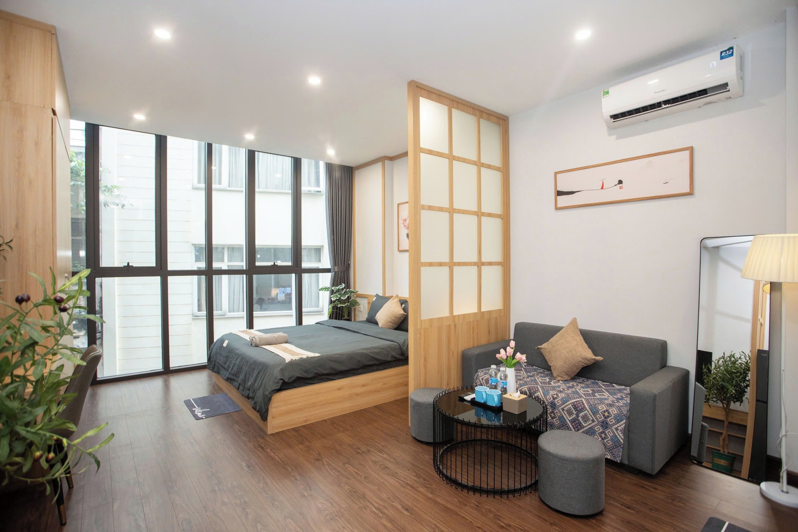 Une chambre moderne avec un lit, un canapé, une petite table et une grande fenêtre.