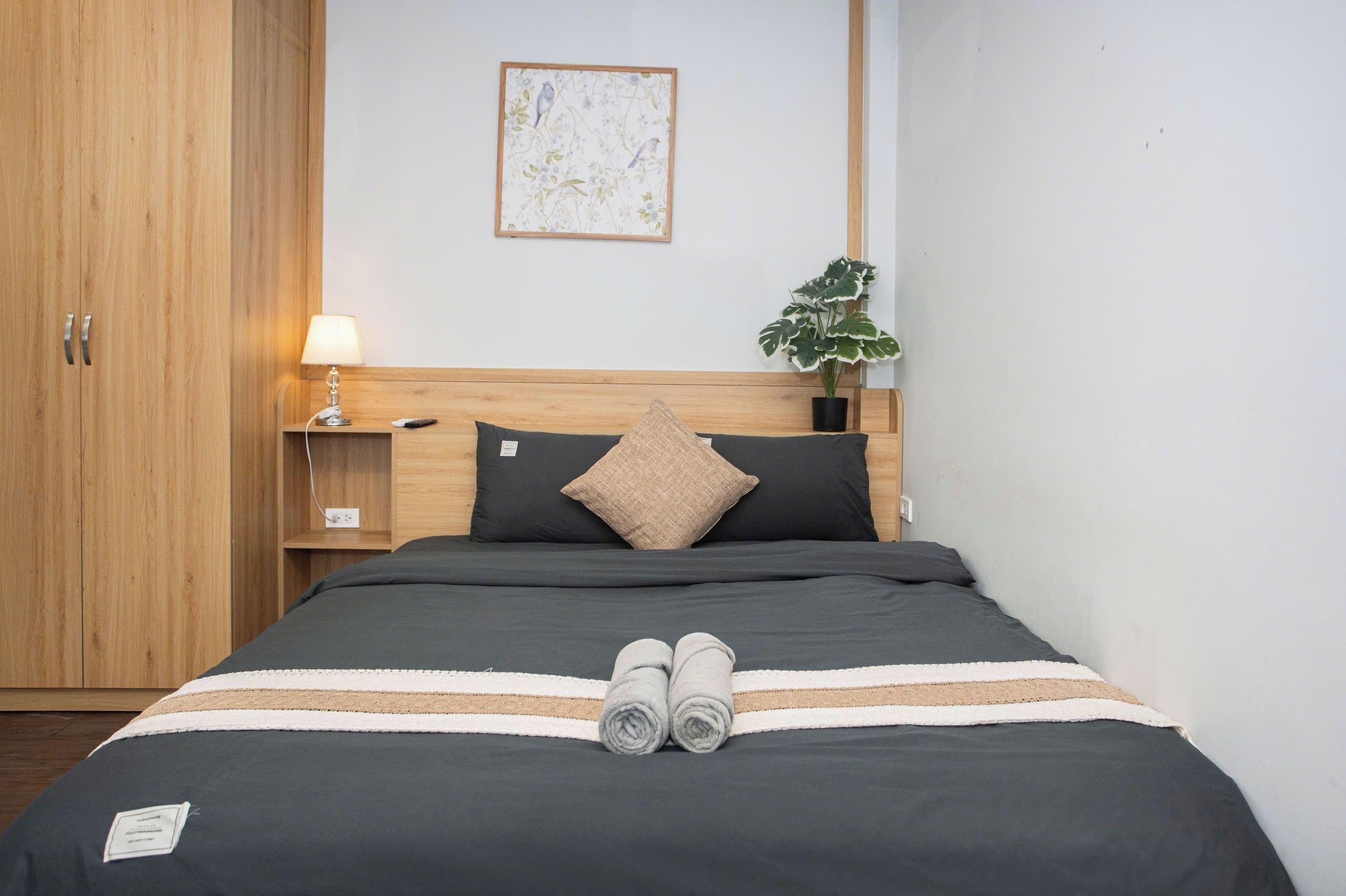 A neatly made bed with a black and white striped blanket, two rolled towels, and a single pillow.