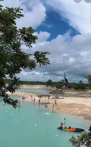 A water body with people kayaking and a person on a zip line.