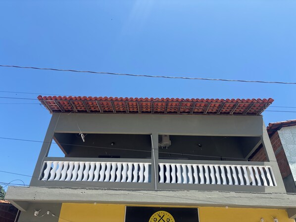 A building with a balcony, a clock, and a tiled roof.