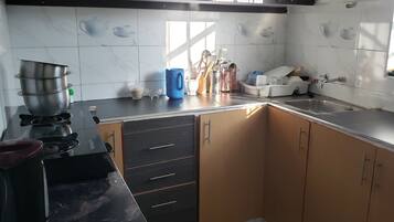 Une cuisine équipée d’une cuisinière, d’un évier, de placards et de divers ustensiles.
