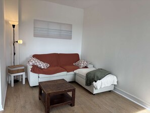 A living room with a sofa, a small table, a floor lamp, and a painting on the wall. - Appartement rénové, résidence avec piscine (BISCARROSSE)