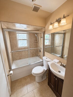 A bathroom with a glass-enclosed shower, a toilet, and a sink. - Luxury 3BR Queens Getaway; Smart TVs, A/C & Near JFK, LGA and UBS Arena (St Albans)