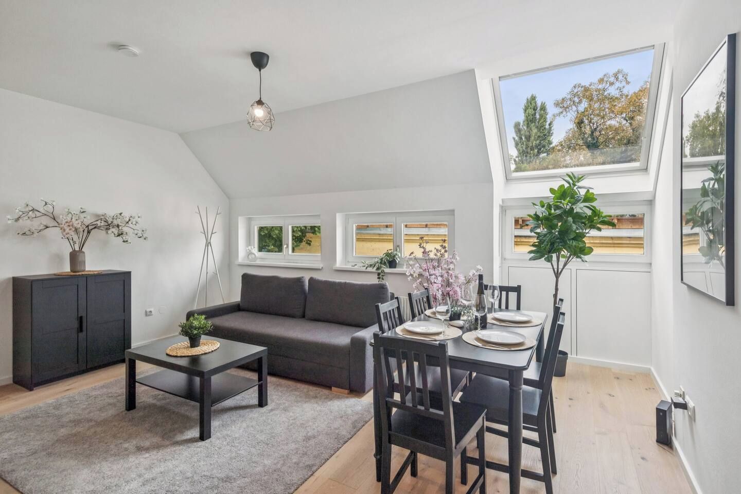 A modern loft apartment with a dining area, a sofa, a coffee table, and a dining table set for four.