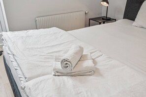A neatly made bed with a rolled towel, a bedside lamp, and a radiator in the background. - Modern Stay near Kahlenberg & Vineyards (Wien)