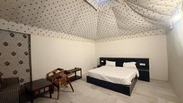 A bedroom with a bed, a desk, and a chair.