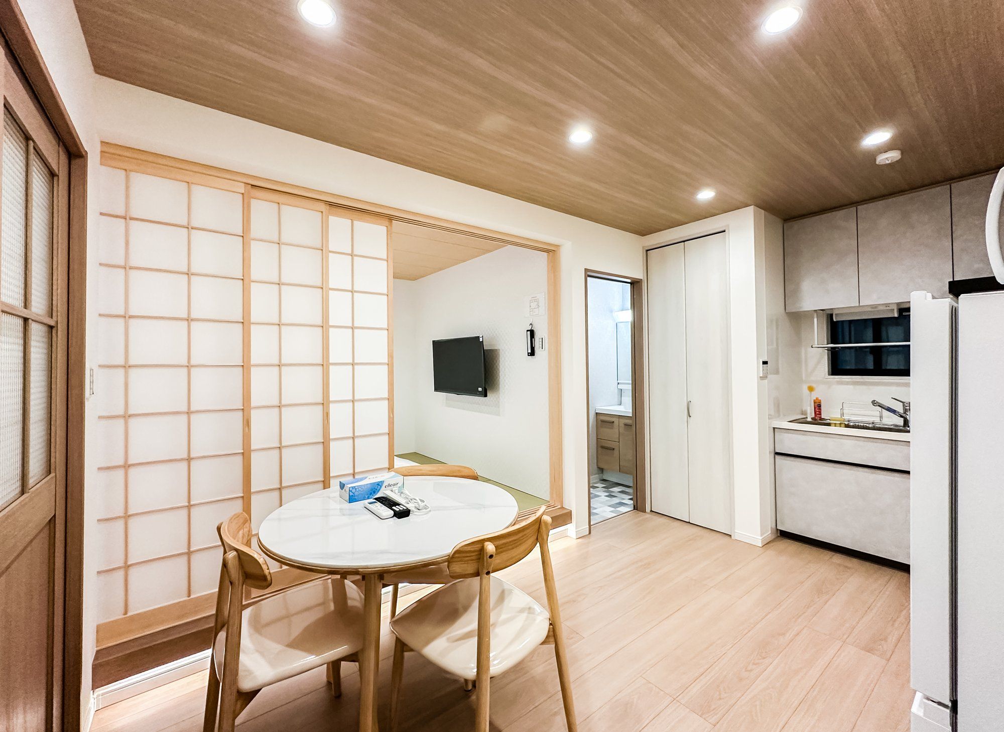 A modern kitchen with a built-in refrigerator, a dining area with a round table and chairs, and a traditional sliding door.