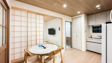 A modern kitchen with a built-in refrigerator, a dining area with a round table and chairs, and a traditional sliding door.